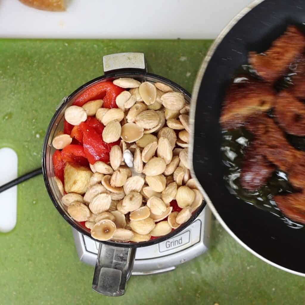 adding romesco sauce ingredients to a food process to blend for roasted cauliflower with romesco sauce