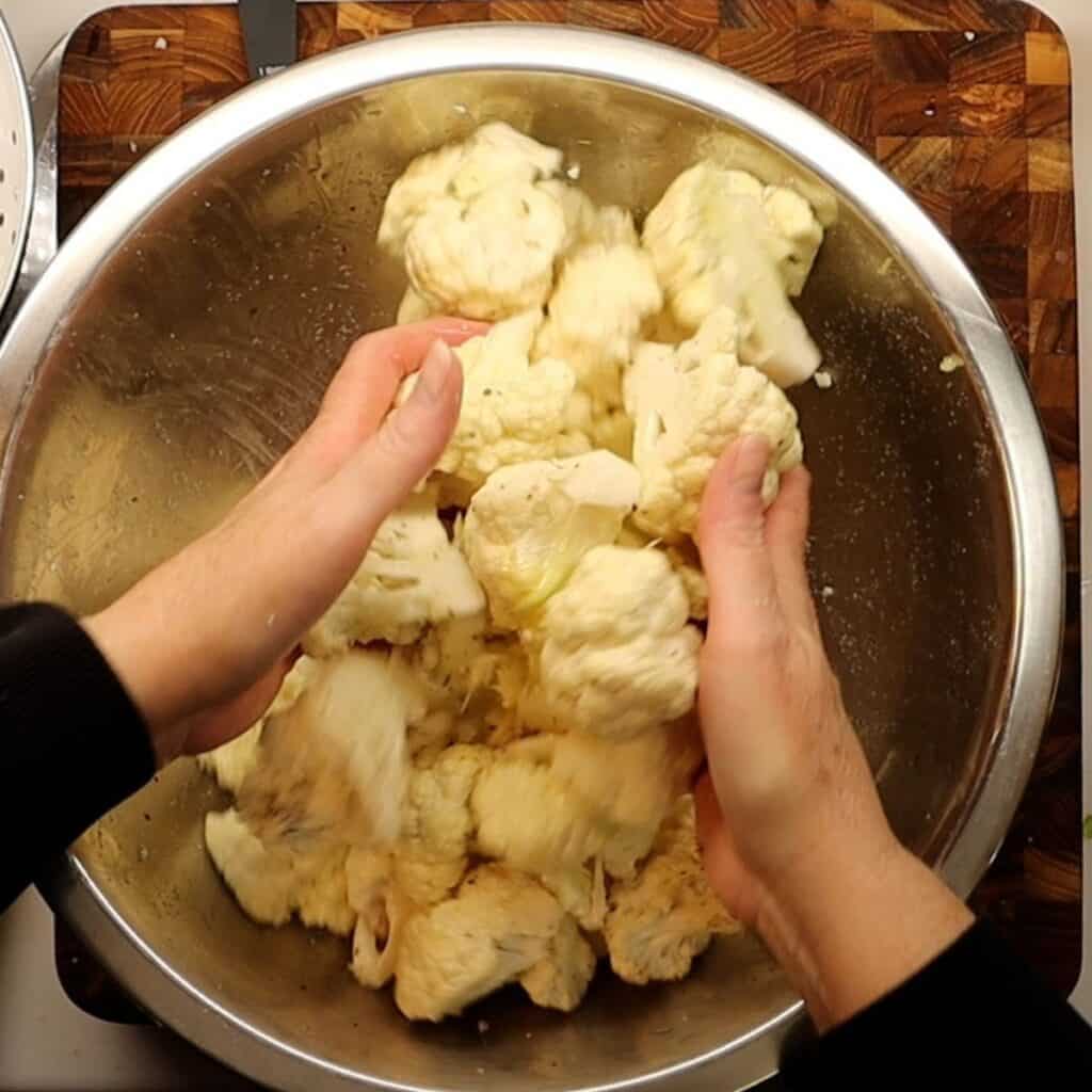 coating chopped cauliflower with olive oil, salt and pepper