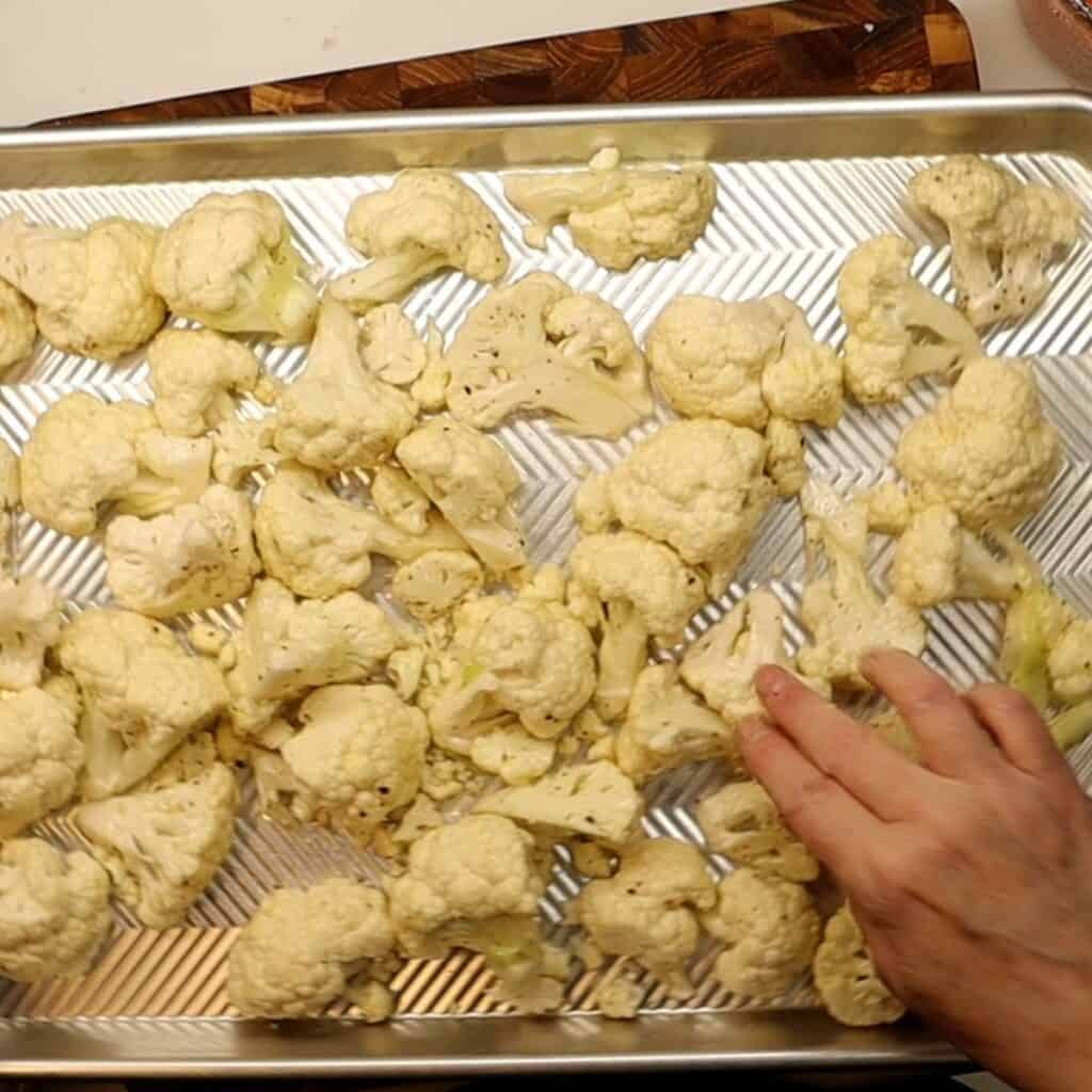 laying out chopped cauliflower on a sheet pan for roasted cauliflower with romesco sauce